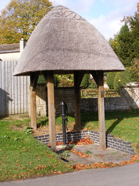 The village water pump, with its thatched roof.